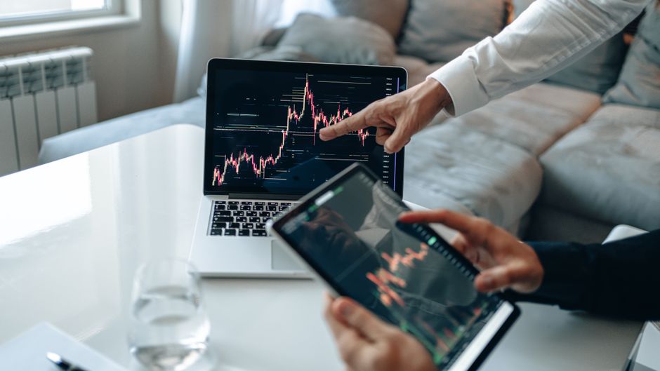 태블릿 화면에 급격히 상승하는 부동산 가치 그래프를 손가락으로 가리키는 모습.