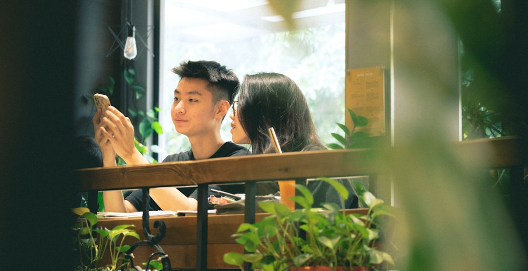 경제 뉴스 헤드라인이 보이는 스마트폰을 보며 최저임금 논란에 대해 이야기하는 두 사람